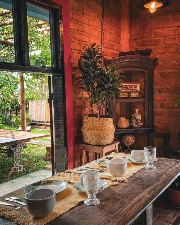 Mesa posta no salão de tijolo aparente, com a porta aberta para o jardim