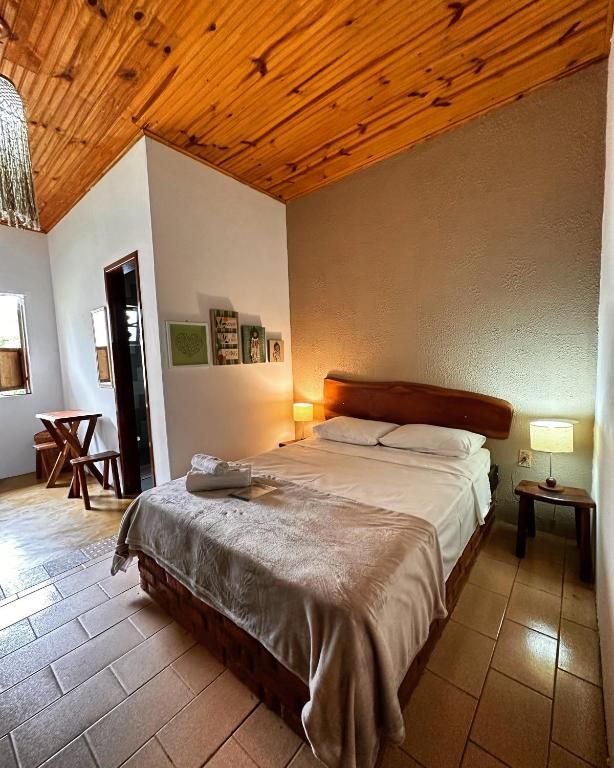 Suíte com forro de madeira, cama de casal e abajures